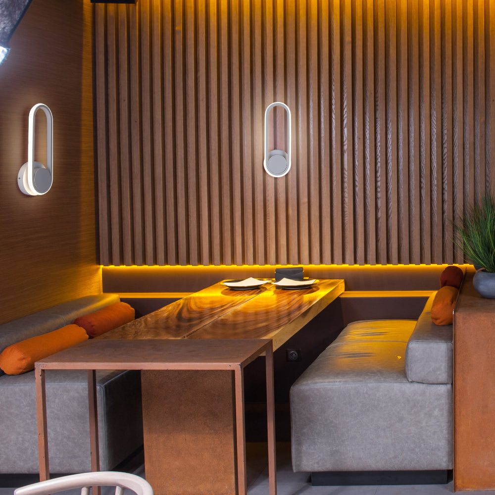 Aplique de pared LED en forma ovalada, ideal para espacios modernos como oficinas y salones, con un diseño elegante y funcional.