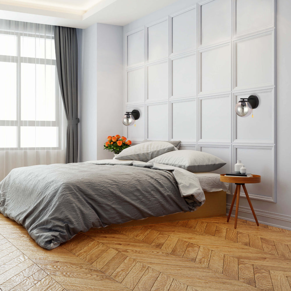 Aplique de pared moderno con cuerpo de metal cromado y globo de vidrio ahumado, ideal para salas con decoración contemporánea.