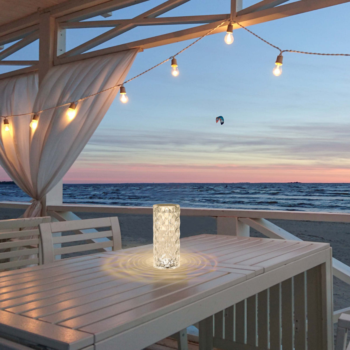 Lámpara cilíndrica recargable con acabado en cristal, perfecta para espacios contemporáneos como salones o terrazas elegantemente decoradas.