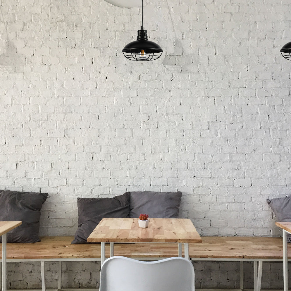 Lámpara colgante de estilo industrial con jaula negra, perfecta para cocinas o comedores modernos.