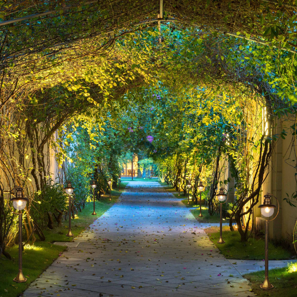 Luz bollard de jardín negra con detalles dorados, perfecta para iluminar caminos en exteriores con estilo contemporáneo.