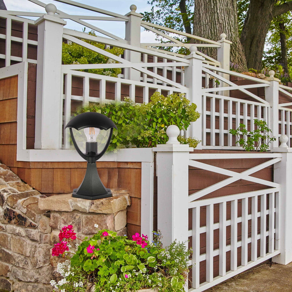 Lámpara de pedestal exterior en forma de farol negro, ideal para patios y jardines con estilo contemporáneo.