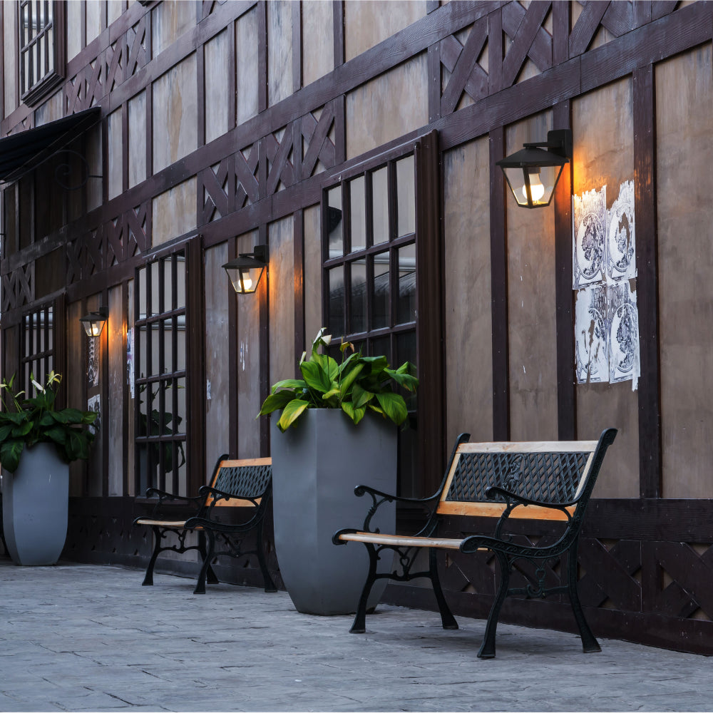 Lámpara de pared tipo farol exterior, perfecta para patios con estilo rústico, ofreciendo calidez y ambientación acogedora.