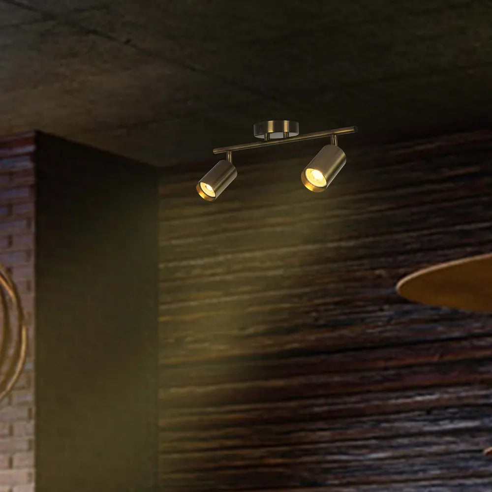 Barra de focos GU10 de latón envejecido iluminando una sala de estar moderna con decoración industrial, realzando calidez y estilo.172-030622