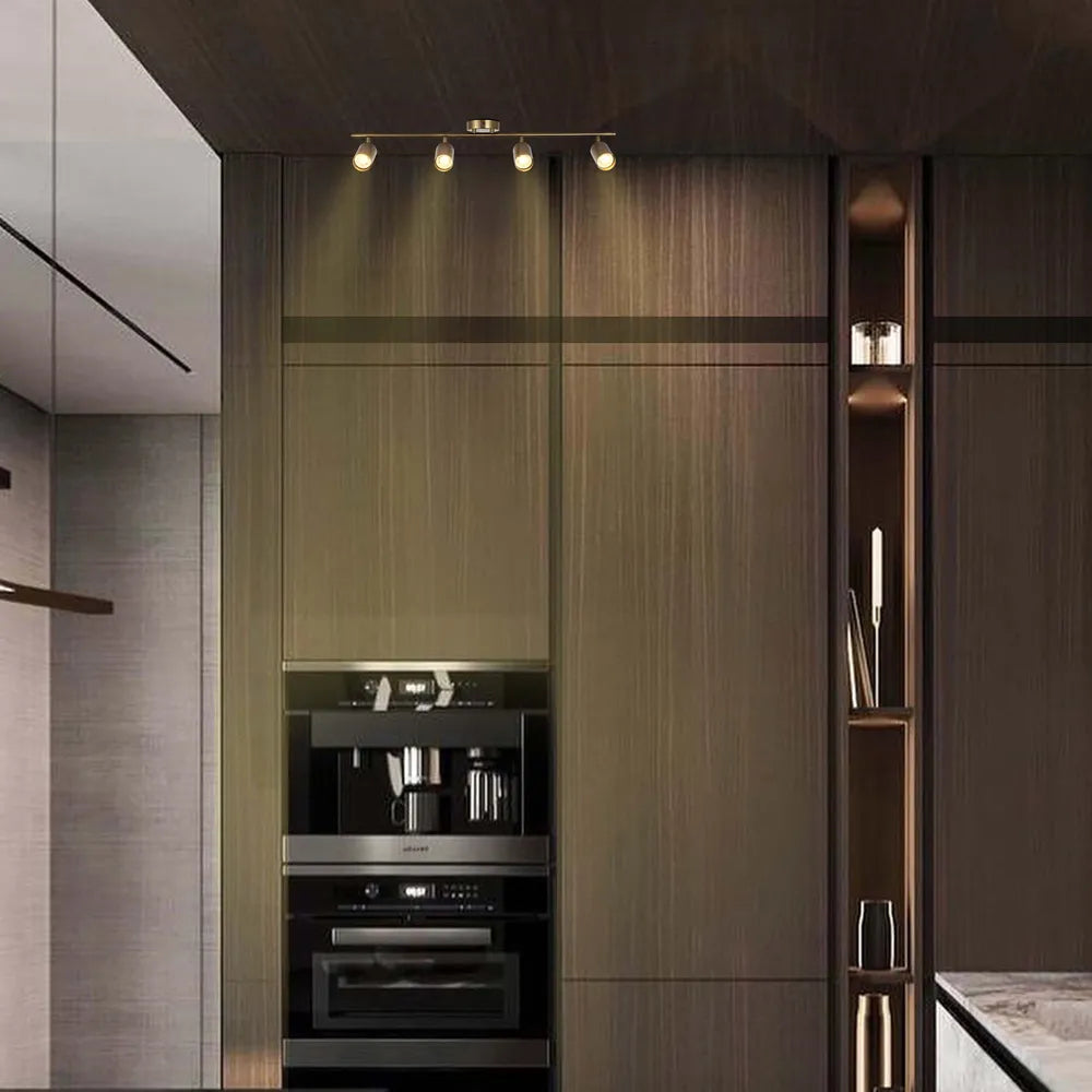Barra de focos GU10 de latón antiguo iluminando una cocina moderna, realzando su decoración elegante y proporcionando iluminación focalizada para tareas.