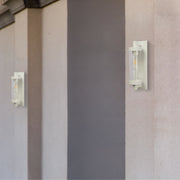Lámpara de pared de vidrio y aluminio en un jardín moderno, ideal para exteriores e interiores con estilo elegante y atemporal.