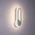 Aplique de pared LED en forma elíptica, ideal para espacios modernos con decoración minimalista y luz blanca fría.