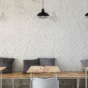 Lámpara colgante de estilo industrial con jaula negra, perfecta para cocinas o comedores modernos.