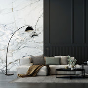 Lámpara de pie curva con pantalla de cúpula negra, ideal para salas de estar con decoración moderna y elegante.