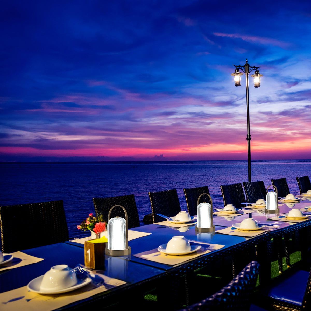Lámpara de mesa portátil en uso en un ambiente exterior moderno, ideal para crear un ambiente acogedor durante la noche.