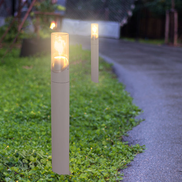 Luz exterior de bolardo con diseño elegante, ideal para senderos y cercas en jardines de estilo contemporáneo.