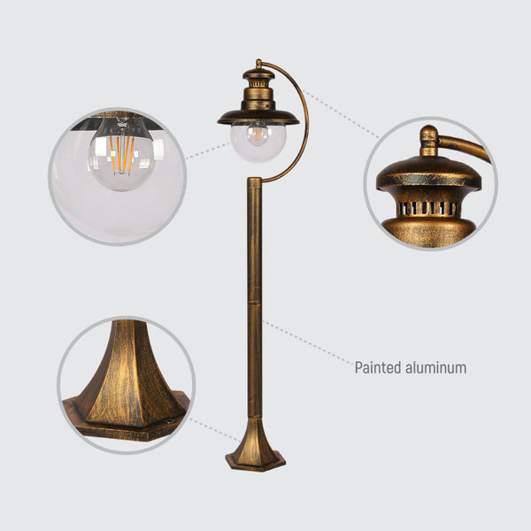 Luz exterior tipo bolardo negra con detalles dorados, perfecta para iluminar caminos en jardines con estilo moderno.